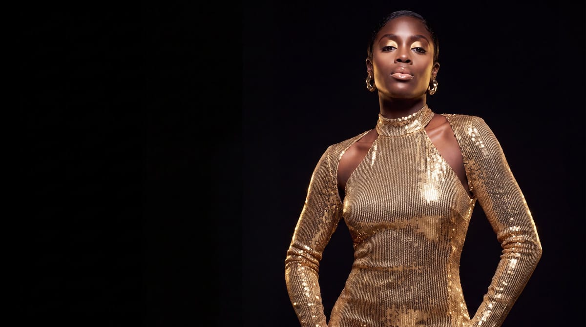 Celeste in a gold sequined gown against a black backdrop