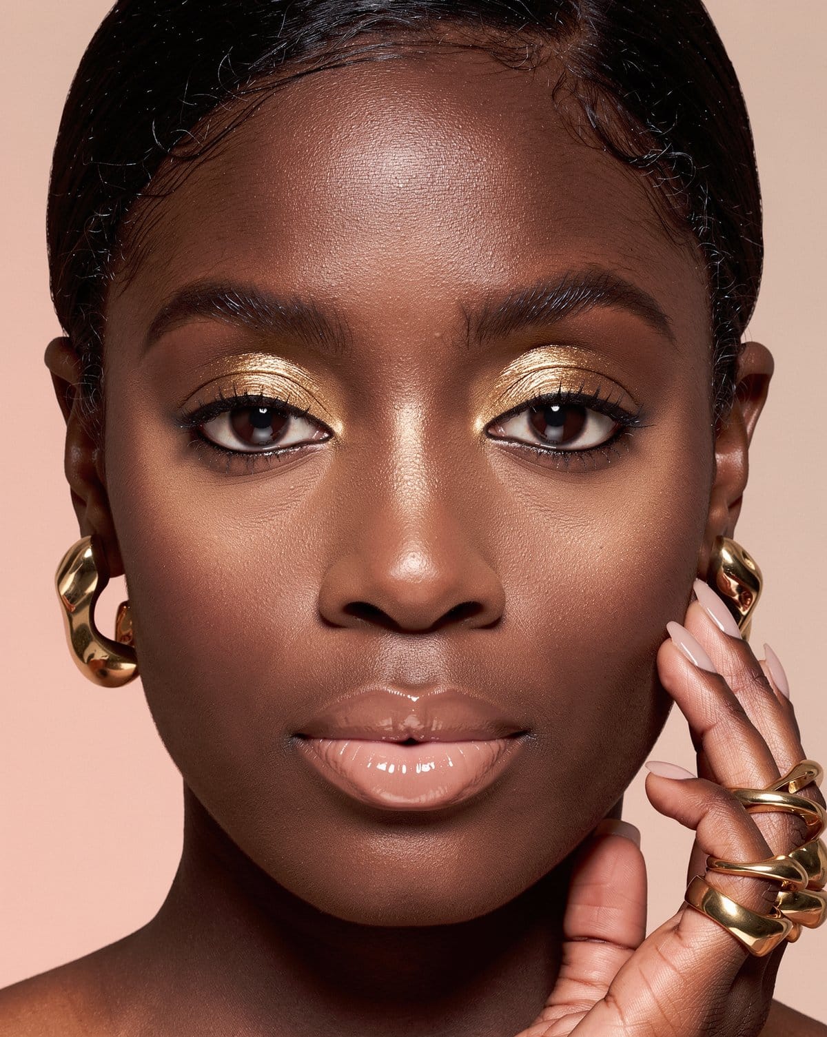 A close portrait of Celeste with gold eye makeup and gold rings
